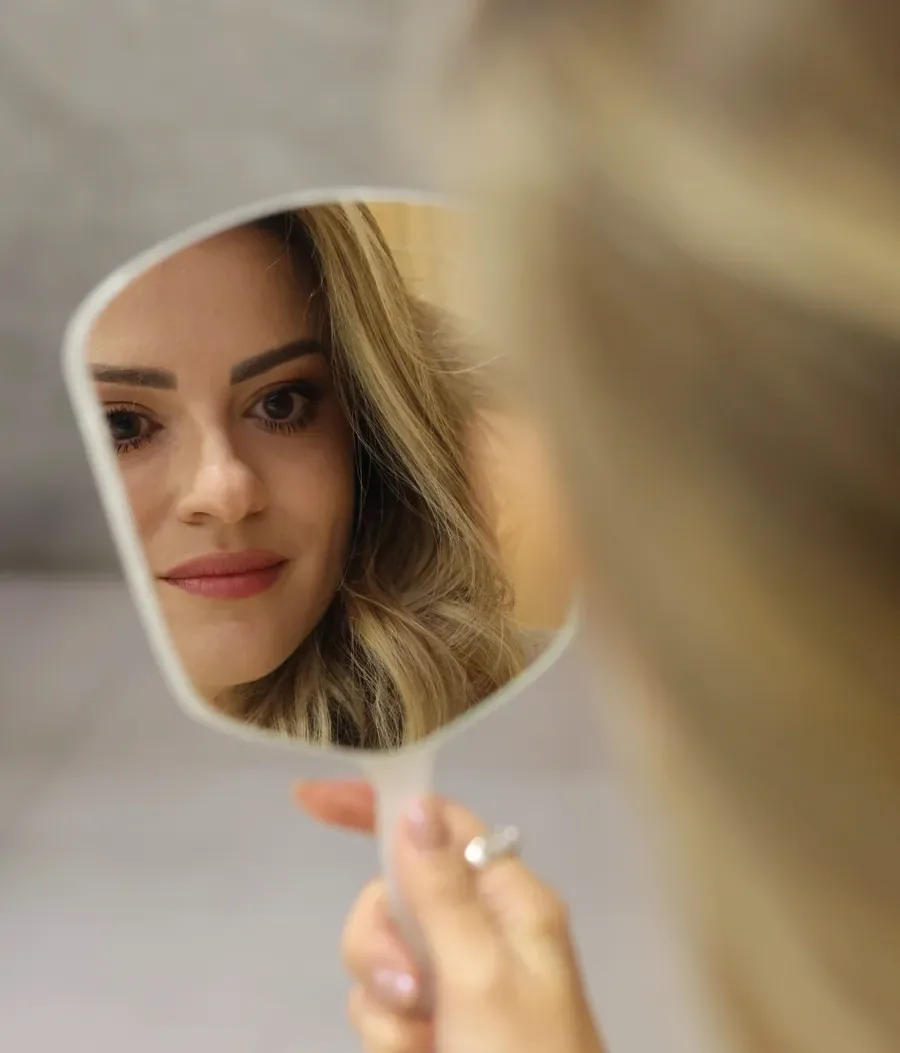 Paciente se olhando no espelho de mão, observando a região dos olhos